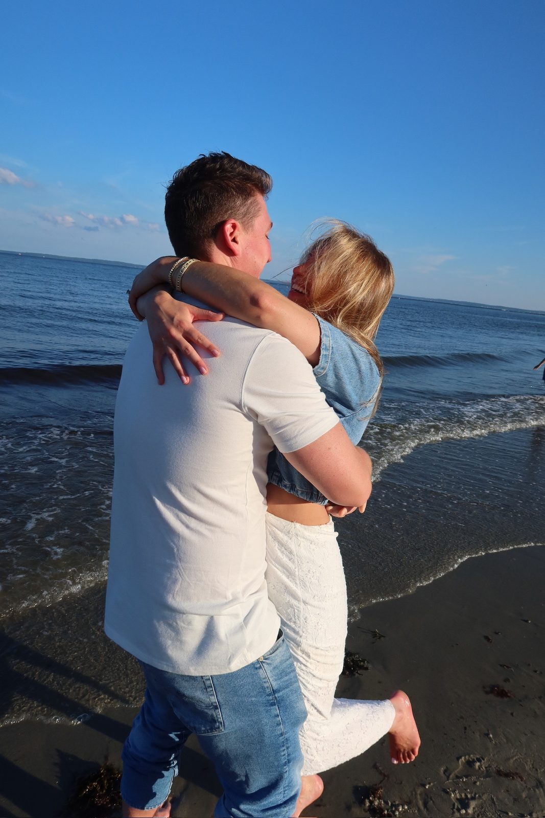 Andrew lifting Jenna off her feet at the shoreline