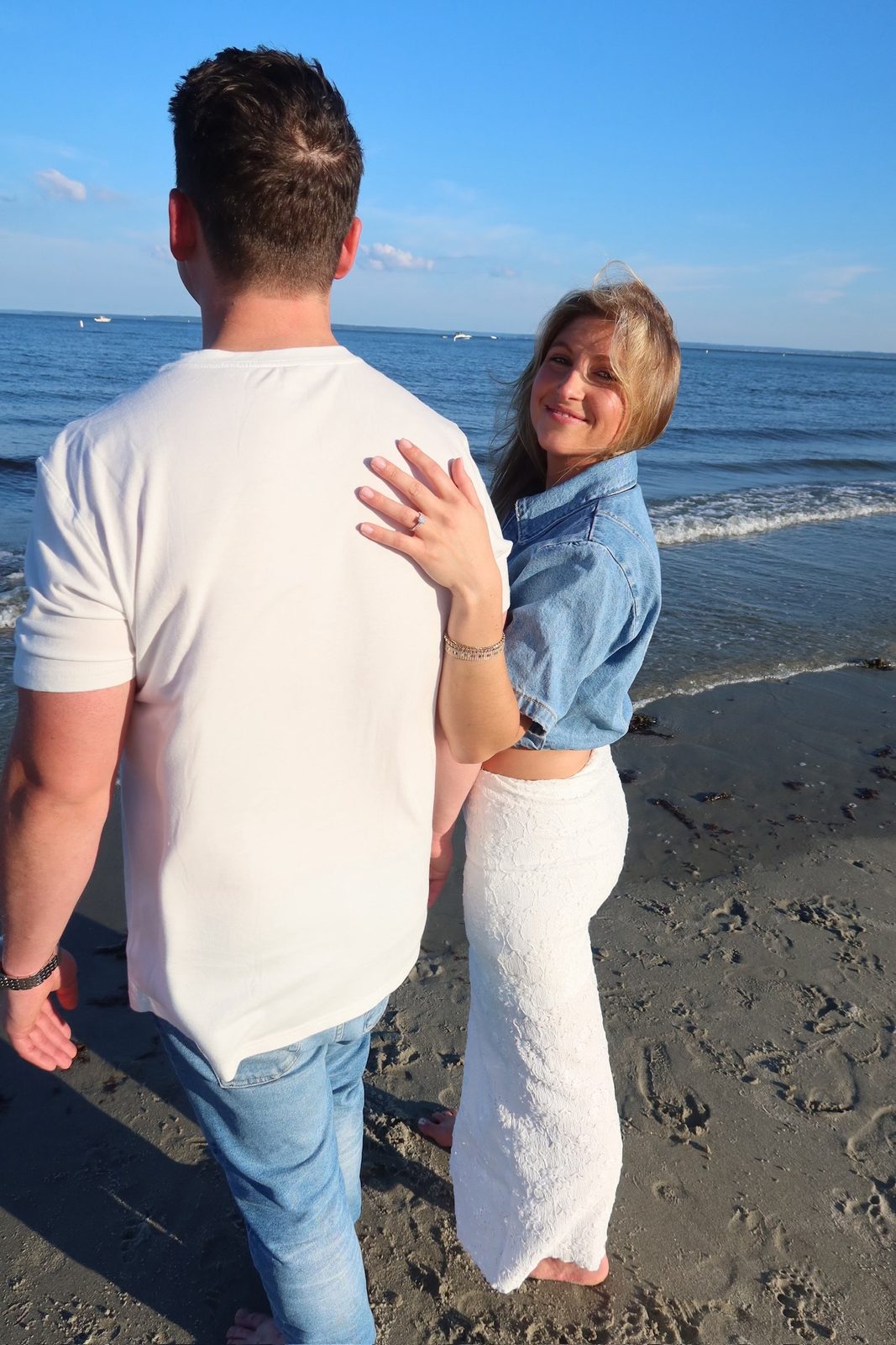 Jenna glancing back over her shoulder with her ring hand resting on Andrew's back
