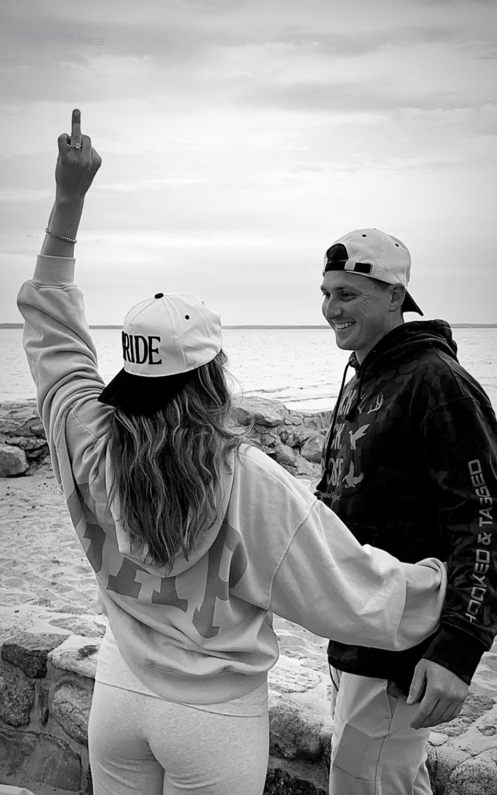 Jenna in her BRIDE hat showing off the ring while Andrew laughs