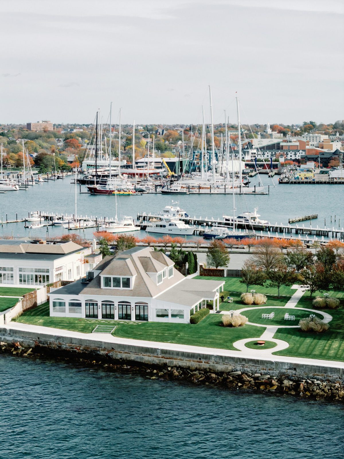 Aerial view of Belle Mer's Island House and oceanfront lawns on Goat Island, Newport Harbor behind